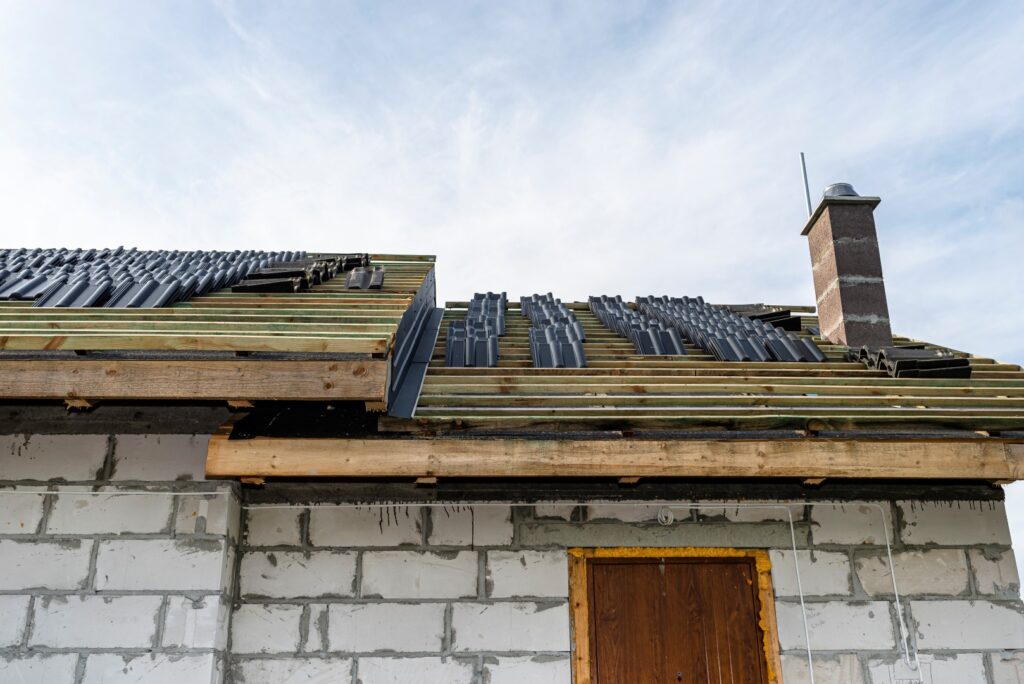 Roof installation preparation with ceramic tiles arranged in packets, ready for laying on a wooden batten structure.