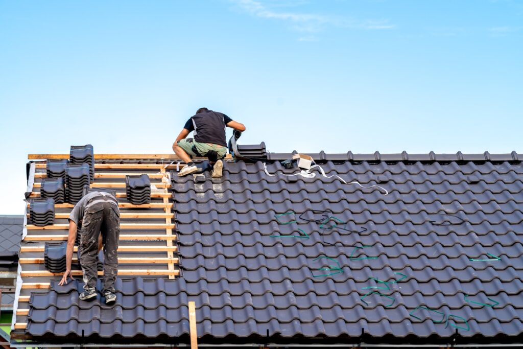 Professional roofing team installing ceramic tiles during roofing services.